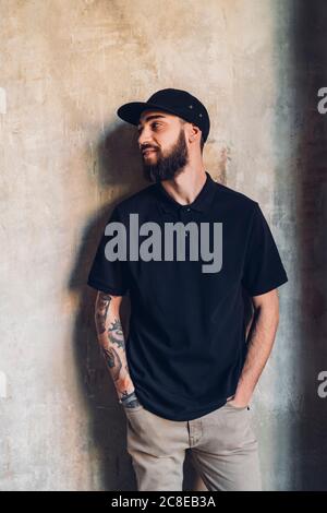 Smiling stylish young man standing at a wall Stock Photo