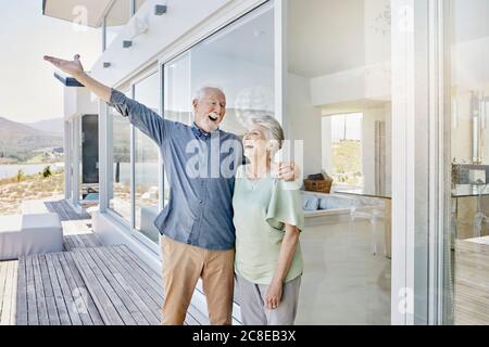 Carefree senior couple standing at luxury beach house Stock Photo