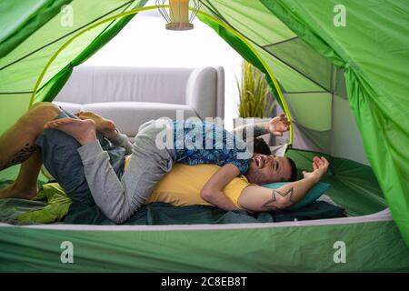 Father and son tussling in tent at home Stock Photo