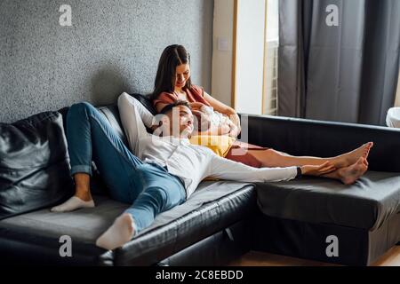 Man lying by mother breastfeeding baby boy in sofa at home Stock Photo