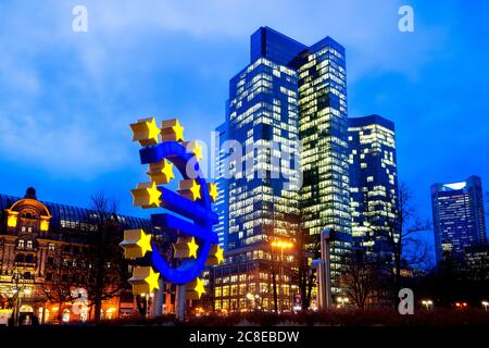 Germany, Hesse, Frankfurt, Euro Sculpture at dusk with skyscrapers in background Stock Photo