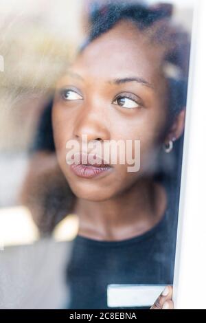 Portrait of young woman with dreadlocks looking out of the window Stock Photo