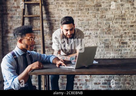 Two creative businessmen using laptop in loft office Stock Photo