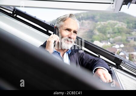 Close-up of male architect talking over smart phone in house seen through window Stock Photo