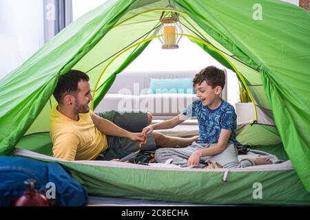 Father and son sitting in tent at home Stock Photo