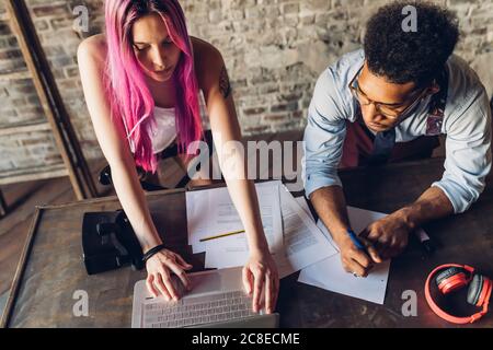 Two creative business people working with laptop and papers on wooden table Stock Photo