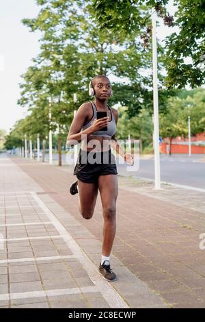 Athlete running woman runner listening to music on her phone