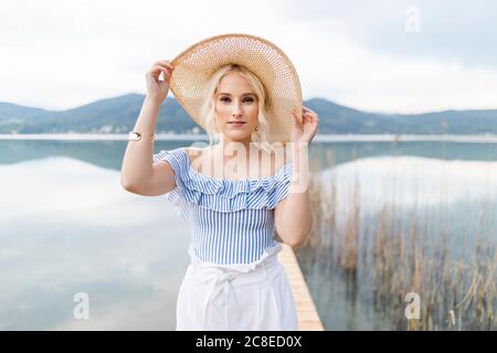 Portrait of fashionable blond woman standing on jetty at Woerthersee, Austria Stock Photo