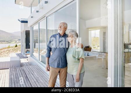 Happy senior couple standing at luxury beach house Stock Photo