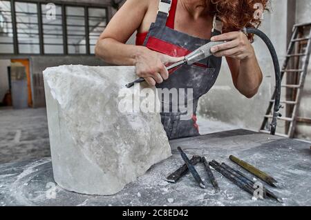 Stonemason carving stone with jackhammer on table in workshop Stock Photo