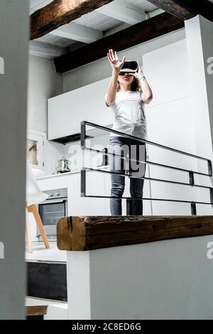 Young woman using Virtual Reality Glasses at home Stock Photo