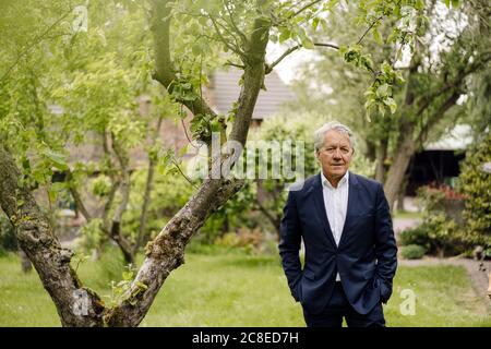 Portrait of a confident senior businessman standing at a tree in a rural garden Stock Photo