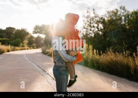 Mother holding her daughter on way outdoors Stock Photo