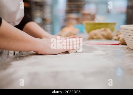 Female baker kneading bread dough in bakery Stock Photo
