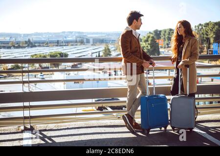 Business couple talking while standing on elevated walkway at airport Stock Photo
