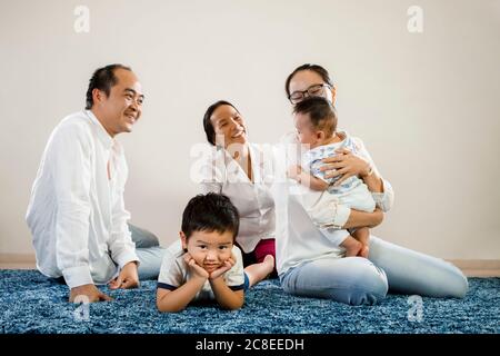 New sibling asian baby brother gets all the attention, jealous older sibling foreground with parents playing with new born younger child. asian family Stock Photo