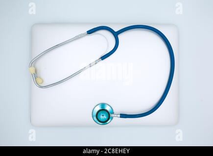 Computer repair, reparation business concept. A laptop with blue stethoscope isolated on a white background. Top view, flat lay image Stock Photo