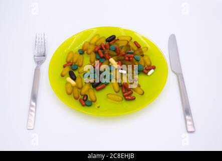 Many different weight loss pills and supplements as food on a green plate with fork and knife. Diet pills and supplements, prescription weight loss dr Stock Photo