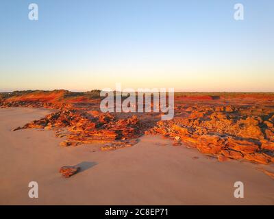 Scenic aerial panoramic view of remote coast near Broome, Western Australia, with ocean beach, red cliffs, outback landscape and sunset blue sky as co Stock Photo