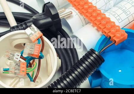 Electrical box, plug and cube with connected electric copper wires and construction drawings of house. Components and accessories for electrical insta Stock Photo