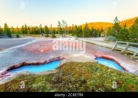 Blue colored hot spring pools at Artists Paintpot Trail at Yellowstone National Park in Wyoming, USA, with late afternoon sun gleaning off the backgro Stock Photo