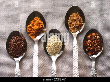 Spices and grains in shiny metal spoons on a napkin. Stock Photo