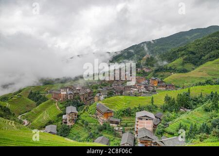 picturesque paddy rice terraces and village houses in Jinkeng, Longji, Guangxi, China during a foggy and cloudy day with occasional rainfall Stock Photo