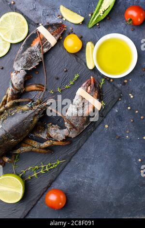 Delicious fresh lobster on dark background. Seafood with aromatic herbs, spices and vegetables - healthy food, diet or cooking concept Stock Photo