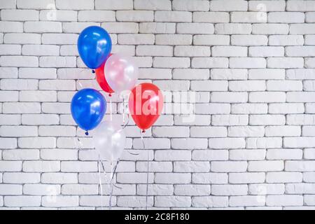Close-up of multi colored balloons against white brick wall background. Space for text. Concept of celebrations Stock Photo