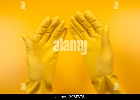 hands in yellow gloves on a yellow background. Stock Photo