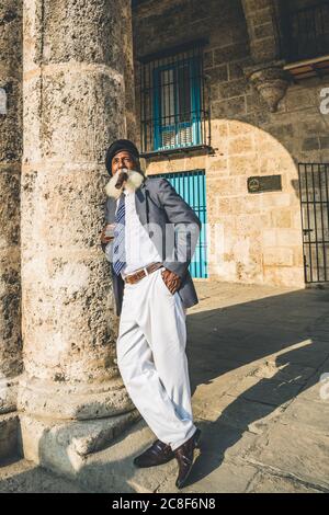 Havana / Cuba - 04.16.2015: Afro cuban old man with a long white beard wearing a suit and a black military beret, smoking a big cigar Stock Photo