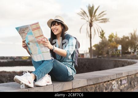 Travel Asian girl looking map during city tour - Young happy woman doing old town excursion discovering new places Stock Photo