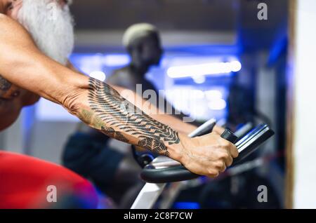 Senior man doing bike exercises in gym - Mature fit male training on cycling machine in health wellness center Stock Photo
