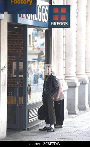 Brighton UK 24th July 2020 -  A man waits outside a Greggs takeaway cafe wearing a face masks in Brighton today after new regulations were brought in by the government at midnight in England in the fight against the coronavirus COVID-19 pandemic : Credit Simon Dack / Alamy Live News Stock Photo