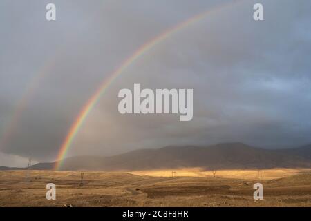 A double rainbow stretches across the landscape on the road from Goris to Shaki road in the south western corner of Armenia. Stock Photo