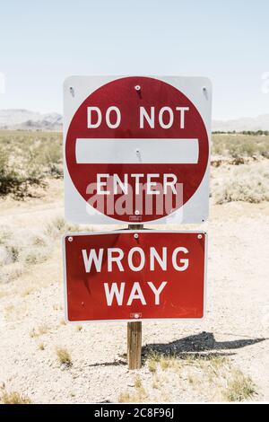vertical shot of red 'Do not Enter' and 'Wrong Way' sign on a deserted street Stock Photo