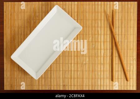 empty rectangular dish with chopsticks on bamboo surface Stock Photo