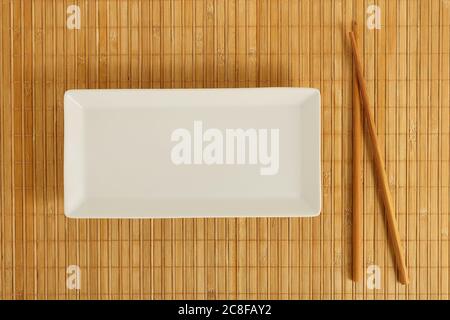 empty rectangular dish with chopsticks on bamboo surface Stock Photo
