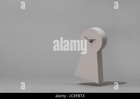 Key hole shaped clock floating just above the surface with plenty of copy space surrounding the clock. Stock Photo