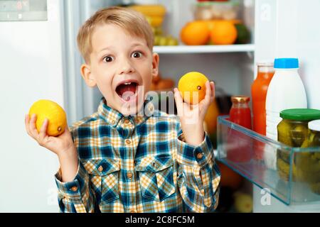 Little boy standing in front of open fridge and choosing food Stock Photo