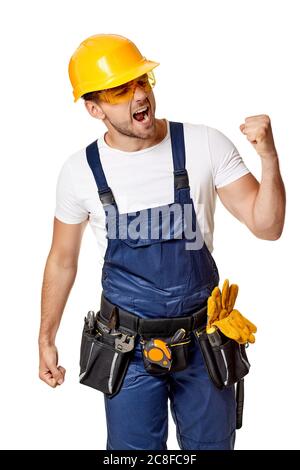 angry caucasian repairman worker in yellow hard hat and uniform. handyman wearing tool belt isolated on white studio background Stock Photo