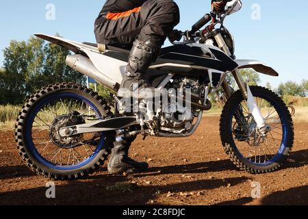 Close-up of unrecognizable motorcyclist in high boots keeping foot on pedal while preparing for race Stock Photo