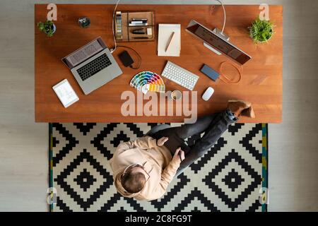 Directly above view of young man keeping feet on table and using drawing pad while working on graphic design Stock Photo