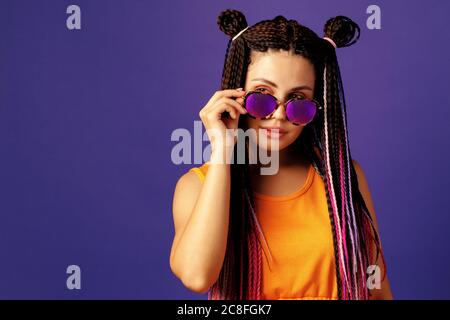 Stylish young woman with afro cornrows wearing purple sunglasses, close up Stock Photo