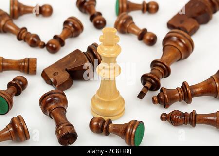 white chess king surrounded by fallen opponents on white Stock Photo
