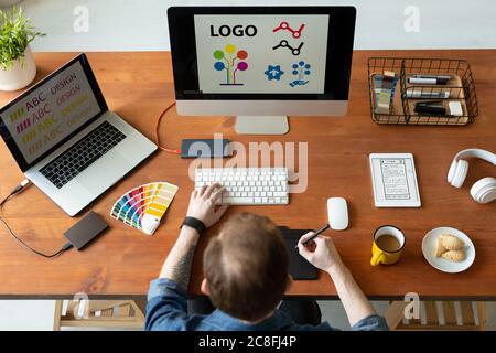 Above view of logo designer sitting at desk and editing icon design using drawing pad Stock Photo