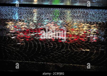 Colorful reflections on cobblestone street at night. Stock Photo