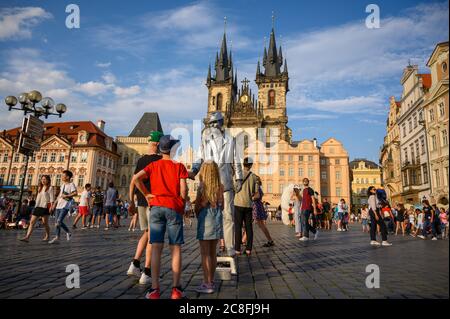 PRAGUE - JULY 20, 2019: Silver statue street performer greeting children in front of The Church of Our Lady before Týn in The Old Town Square, Prague, Stock Photo