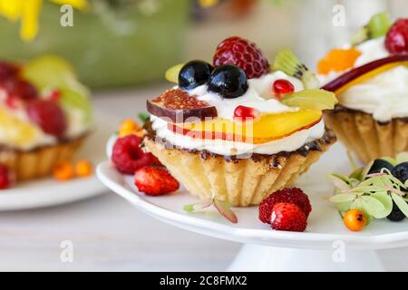 Colorful cupcakes and floral arrangement with sunflowers and hortensias on party table. Stock Photo