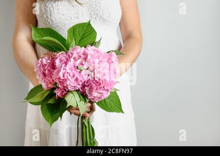 Woman in white dress with bouquet of pink hydrangea flower. Flowers delivery. Floral shop concept. Handsome freshly plucked bouquet. Banner with copy Stock Photo